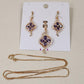 Gold hued jewelry set with clear and purple stones 