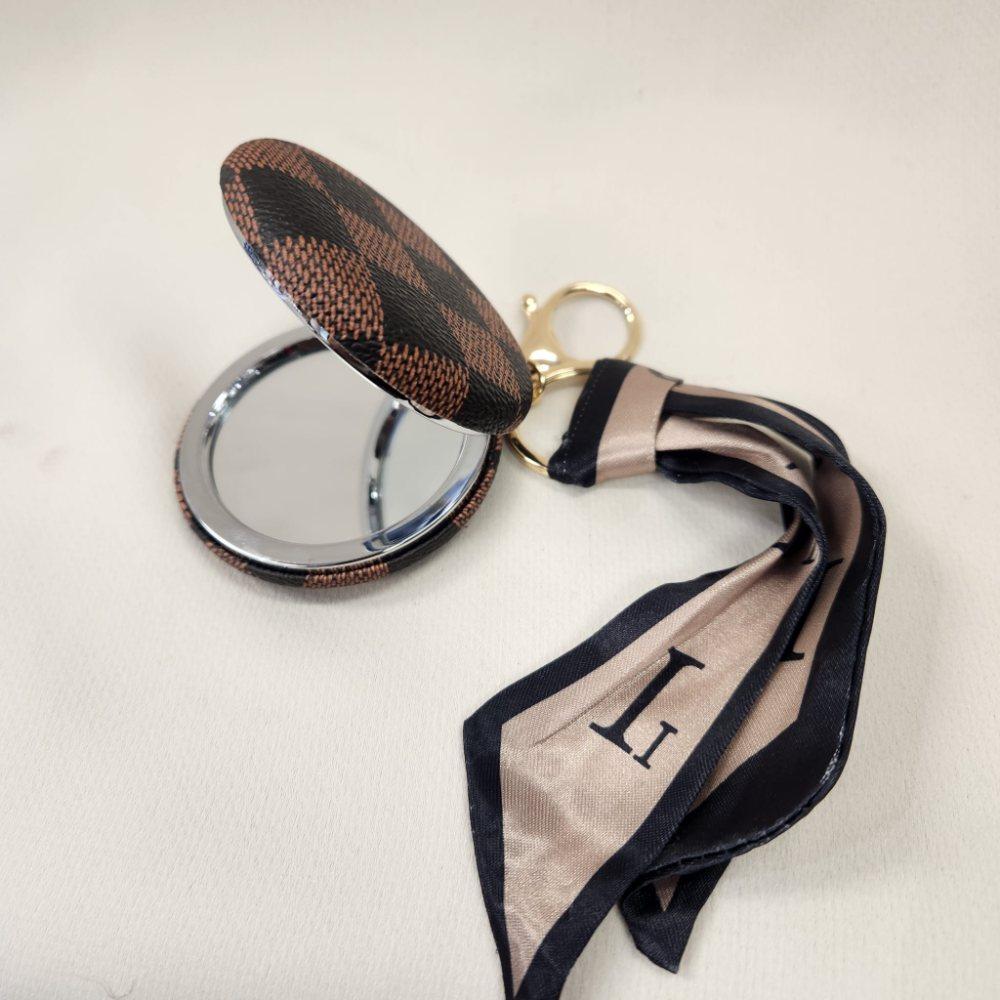 Pocket mirror with brown checkered print and a keyring when opened
