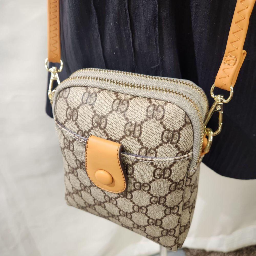 Detailed view of Signature print side bag in beige with brown print and tan straps