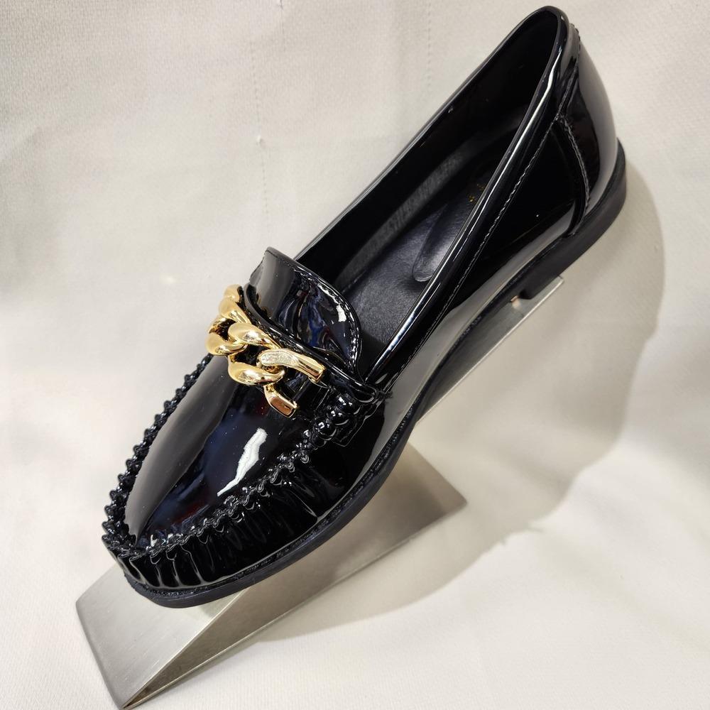 Side view of black patent flat shoes for women with gold buckle