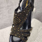 Detailed front view of black upper summer sandals embellished with gold stones