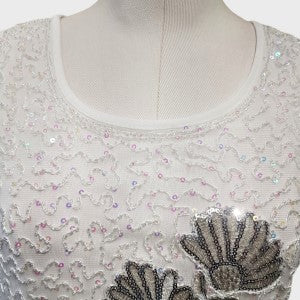 Detailed view of neckline of white top with silver and white sequin work