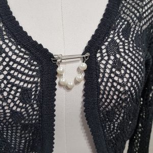 Detailed view of pearl lapel on black crochet shrug 
