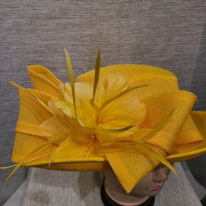 Detailed view of bow and feathers on yellow formal dress hat 