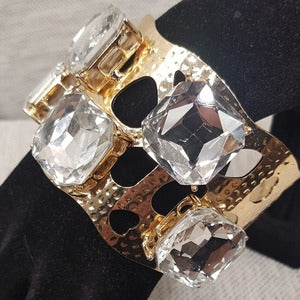 Clear square shaped stones on wide cuff bracelet in gold color