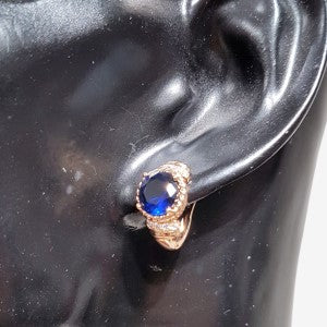 Gold hoop earrings with bright blue center stone.