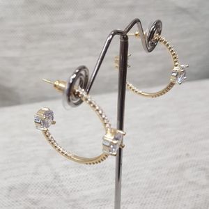 Side view of open hoop gold earrings with stones