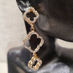 Detailed view of Clover shaped dangle gold earrings with stones