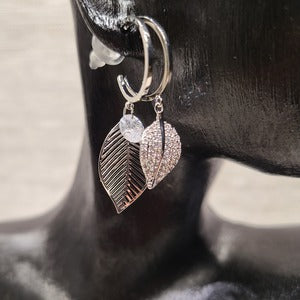Closer view of Silver color hoop earrings with dangling leaf detail