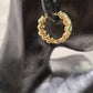 Side view of gold frame hoop earrings with green and white stones