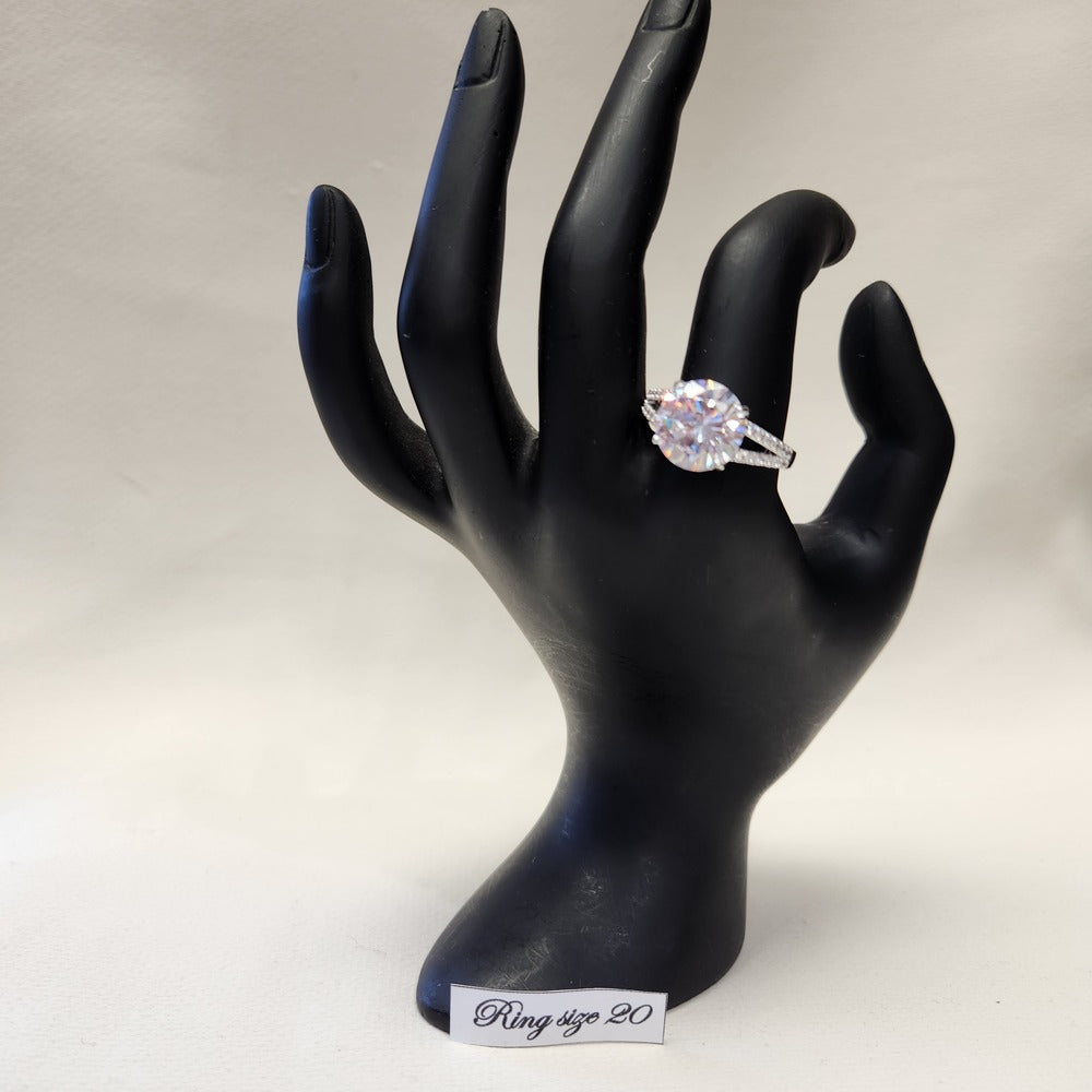 Prong-set silver colored ring with clear stones displayed on mannequin stand
