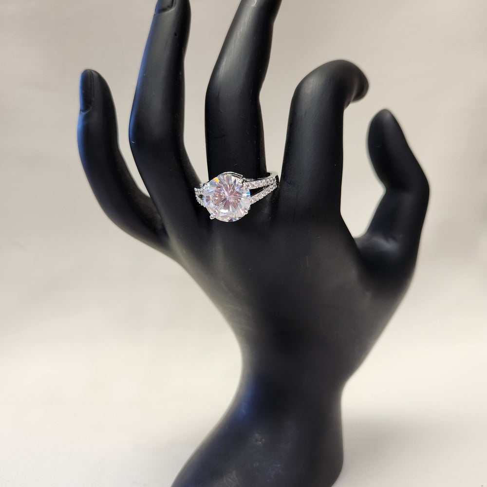 Detailed view of Prong-set silver colored ring with clear stones on mannequin