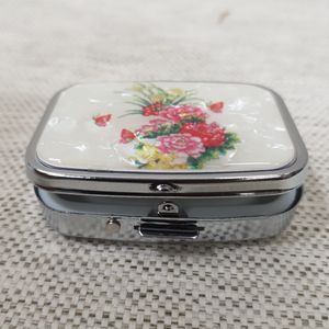 Small metallic pill box with floral pattern