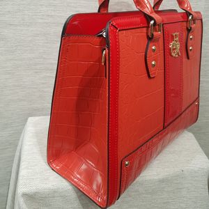 Side view of coral red handbag