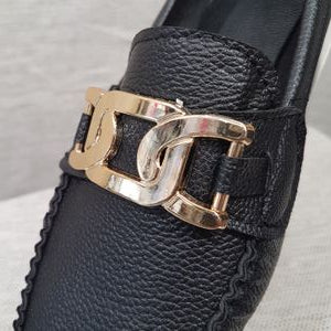 Detailed view of black loafer's top buckle