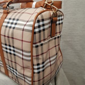 Side view of plaid pattern travel bag with top handle and strap